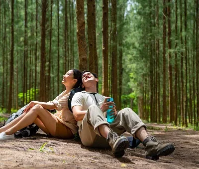 asian couple hiking together in pine tree forest