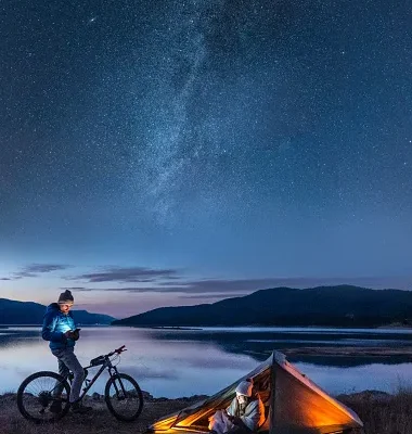 couple under the milky way camping at lake people in nature