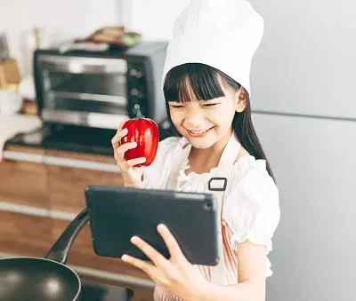 little asian girl with chef hat and apron cooking at home kitchen